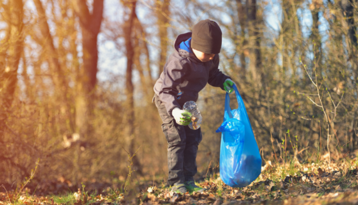 Kid picking up garbage in forest